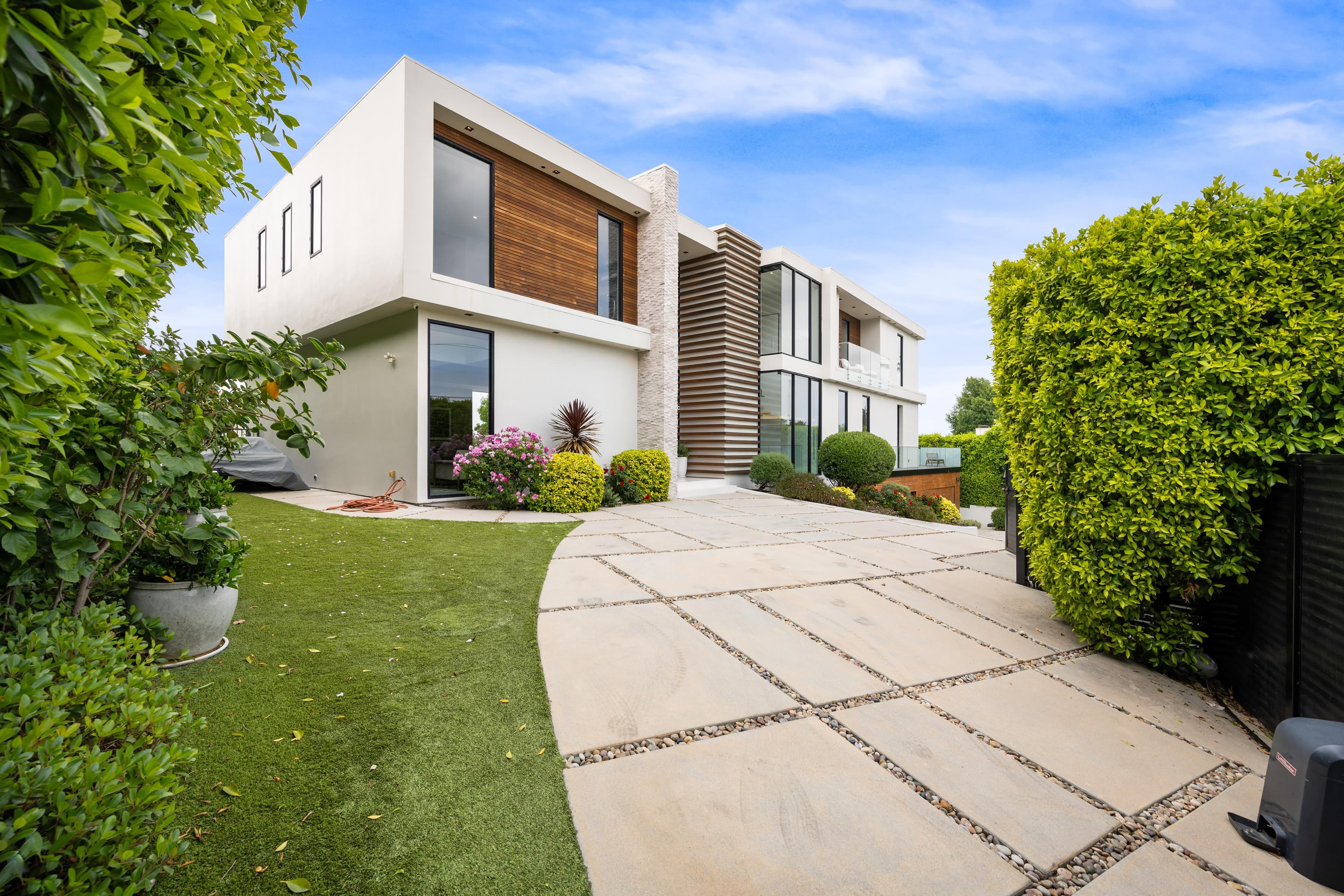 Driveway of a contemporary home with a landscaped garden at dusk — the kind of property we acquire and operate on your behalf